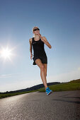 Female runner on road near Munsing, Upper Bavaria, Germany