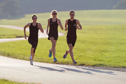 Three runners on road near Munsing, Upper Bavaria, Germany