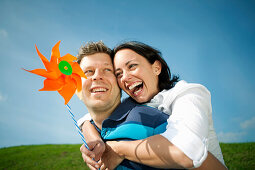 Mid adult man giving woman with pinwheel a piggyback ride, Styria, Austria