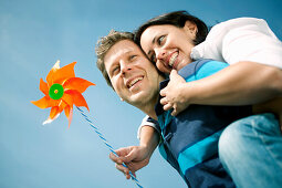 Mid adult man giving woman with pinwheel a piggyback ride, Styria, Austria