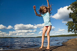 Nine year old girl jumping in the air at Boasjön lake, Smaland, South Sweden, Scandinavia, Europe