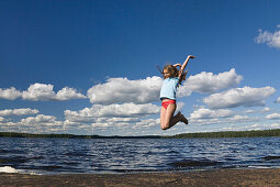 Mädchen (9 Jahre) springt am Boasjön See in die Luft, Smaland, Schweden