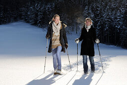 Zwei junge Frauen gehen mit Schneeschuhen über verschneite Wiese, Leitzachtal, Oberbayern, Bayern, Deutschland, Europa