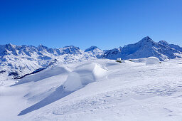 Snow covered boulder with Bernina range in background, Piz Grevasalvas, Albula range, Upper Engadin, Engadin, Grisons, Switzerland, Europe