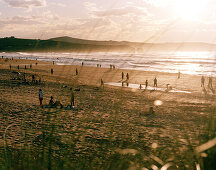 Sunbathers on the beach at sunset, Playa de Valdearenas, west of Santander, Cantabria, Spain