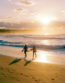 Paar läuft am Strand entlang bei Sonnenuntergang, Playa de Valdearenas, westlich Santander, Kantabrien, Spanien