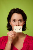 Mid audlt woman holding smiling postit note
