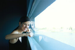 Woman pressing fists against window, smiling at camera