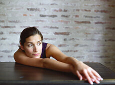 Young woman slouching on table, looking away