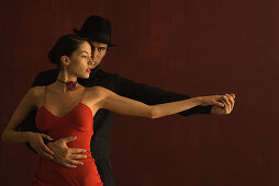 Couple tango dancing together, holding hands, arms outstretched, man looking at camera