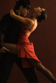 Couple tango dancing together, man holding woman's leg, woman leaning back