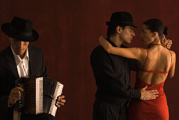Couple dancing together next to male accordion player