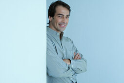 Man leaning against wall, arms folded, smiling at camera