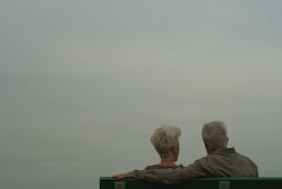 Senior couple sitting on bench, rear view
