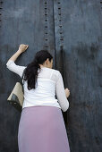 Woman knocking on door, rear view