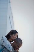 Woman embracing man from behind, kissing back of his head