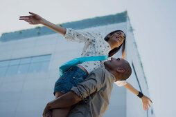 Man lifting woman in air, woman's arms outstretched