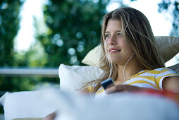 Young woman listening to MP3 player, looking away