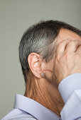 Mature man holding head, cropped