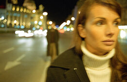 Young woman walking in street at night