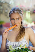 Portrait of a young woman eating carrot
