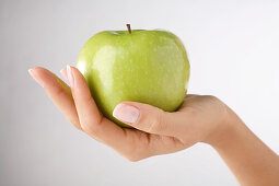 Woman 's hand holding a green apple