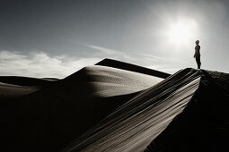 Woman Standing at Top of Desert Sand Dune, California, USA