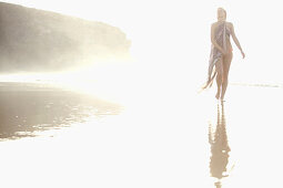 Junge Frau geht durch flaches Wasser am Strand, Fuerteventura, Spanien