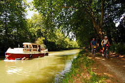 Two cyclists cycling along a path next to the Canal du Midi, Midi, France
