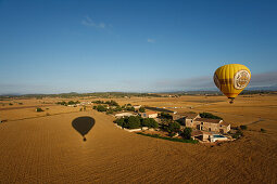 Hot air balloon flying over fields and a farm, plain Es Pla, Mallorca, Balearic Islands, Spain, Europe