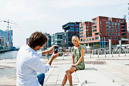 Man taking a photo of a woman at Magellan-Terraces, HafenCity, Hamburg, Germany