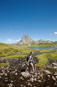 Woman hiking near lake Lac d'Ayous, Pic du Midi d'Ossau in background, Ossau Valley, French Pyrenees, Pyrenees-Atlantiques, Aquitaine, France