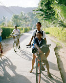 Kinder auf ihren Fahrrädern auf dem Weg zur Grundschule, Anse La Reunion, La Digue, La Digue and Inner Islands, Republik Seychellen, Indischer Ozean