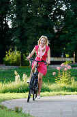 Woman cycling through Rosenstein Park on an e-bike, bike tour, Rosenstein Park, Stuttgart, Baden-Wurttemberg, Germany