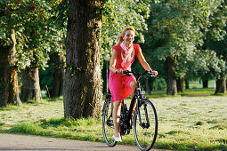 Woman cycling through Rosenstein Park on an E-Bike, bike tour, e-bike, Rosenstein Park, Stuttgart, Baden-Wurttemberg, Germany