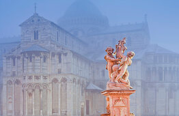 Fountain with statue in front of Santa Maria Assunta cathedral in the fog, Pisa, Tuscany, Italy, Europe
