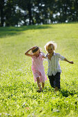 Sibling, 5 and 7 years,  running over a meadow, Lake Starnberg, Bavaria, Germany