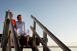 Paar sitzt auf einem Steg am Starnberger See, Bayern, Deutschland