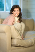 Young woman sitting on a sofa, smiling for the camera