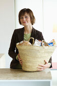 Young smiling woman with shopping basket in the kitchen