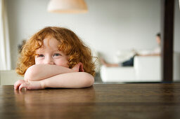 Little girl resting her arms on a coffee table