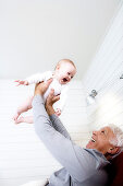 Smiling senior man lifting baby girl in the air