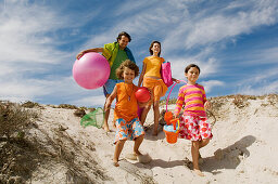 Parents and two children walking on the beach, outdoors