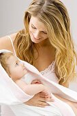 Close-up of a young woman wrapping her son in a towel and smiling