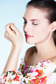 Young woman smelling perfume on her wrist