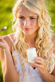 Portrait of young woman eating a yoghurt