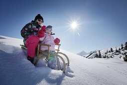 Two girls, 12 and 2 years, on a sledge, Kloesterle, Arlberg, Tyrol, Austria