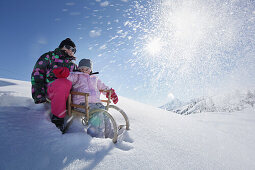 Two girls, 12 and 2 years, on a sledge, Kloesterle, Arlberg, Tyrol, Austria