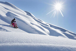 Two girls 12 and 2 years, on a sledge, Kloesterle, Arlberg, Tyrol, Austria