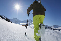 Skifahrer geht zu Berghütte im Schnee, Klösterle, Arlberggebiet, Österreich